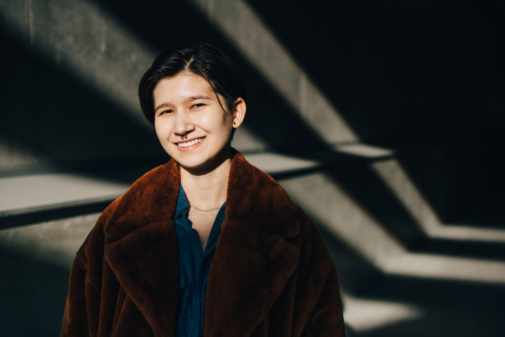 Portrait,Of,Smiling,Young,Woman,Standing,Against,Wall